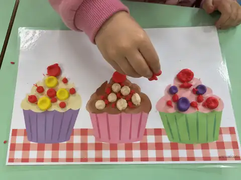 Criança decorando cupcakes com massinha na prancha
